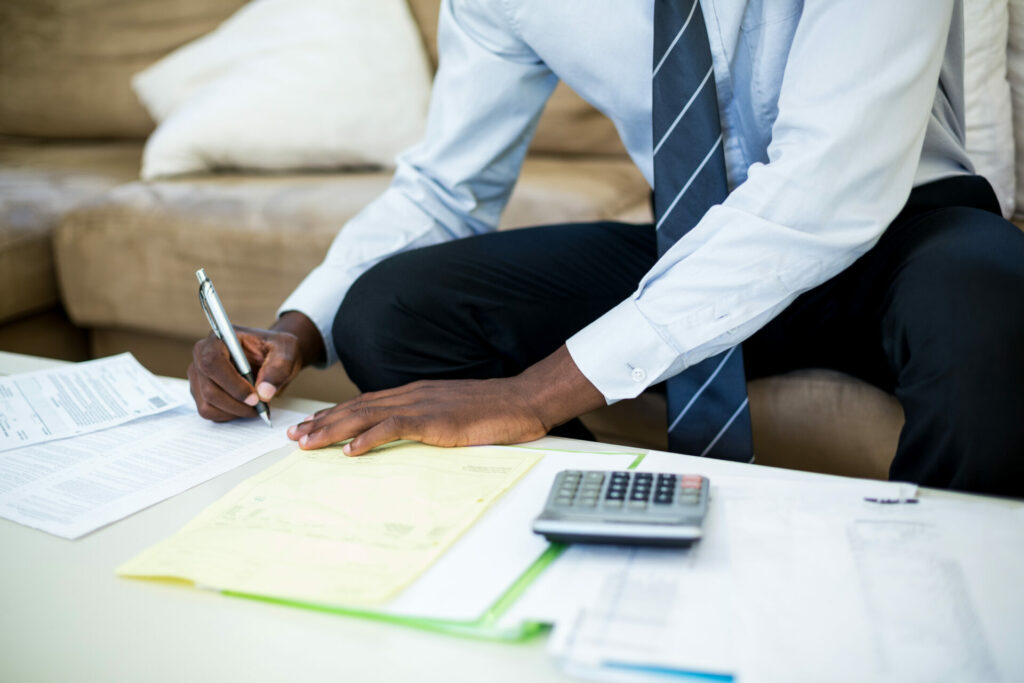 mid section of man sitting on sofa and accounting